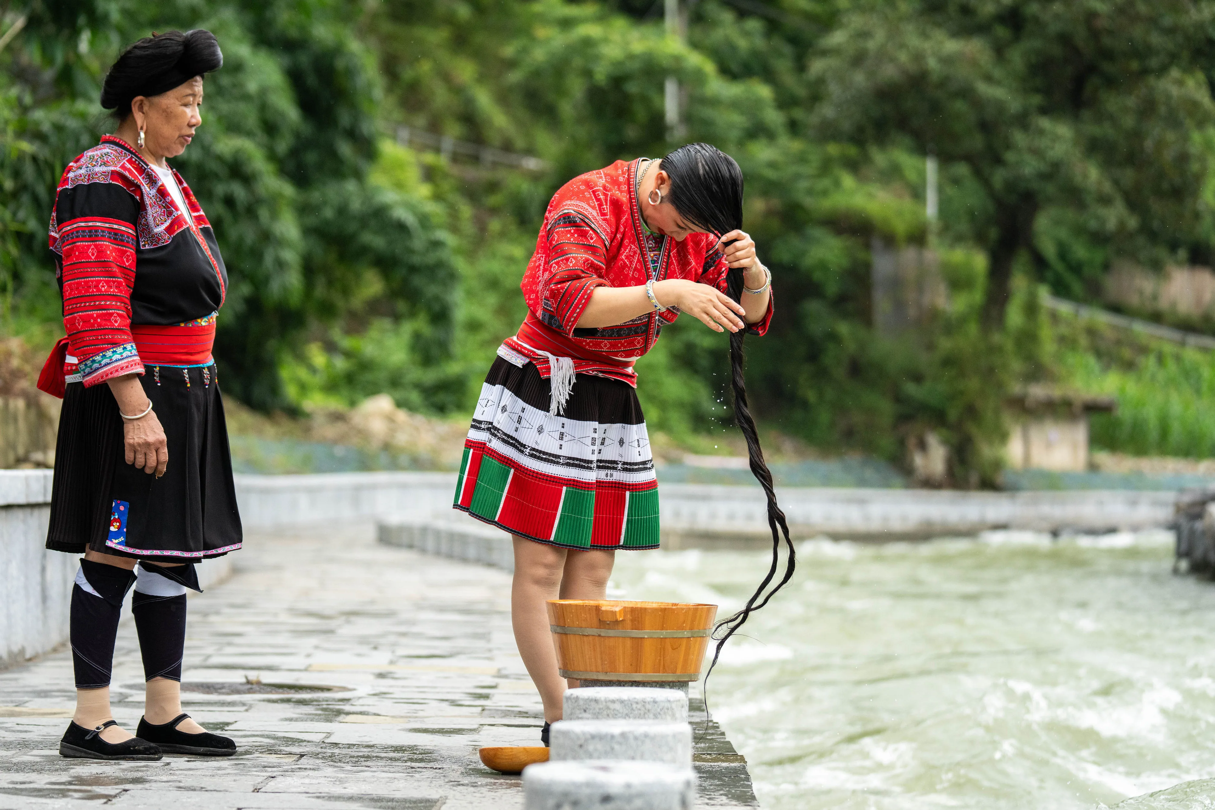 Pan Fengfei (jobbra) helyi lakos hajat mos egy folyó partján Huangluo faluban. A falu az utóbbi években fokozta erőfeszítéseit a turisztikai ipar fejlesztése érdekében, kihasználva etnikai kultúráját, beleértve a ruhaszövést, a táncot és a hosszú haj ápolásának hagyományait. A faluban idén január és június között mintegy 274 800 turista utazott el.